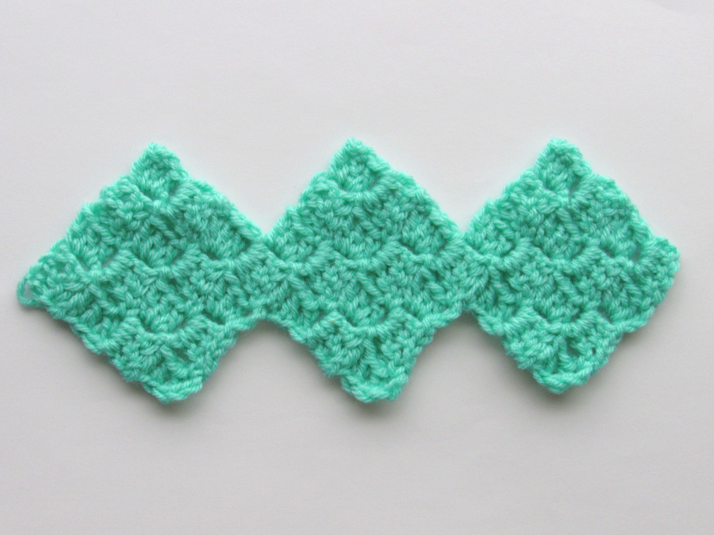 a panel of three connected C2C crochet squares, made of green yarn