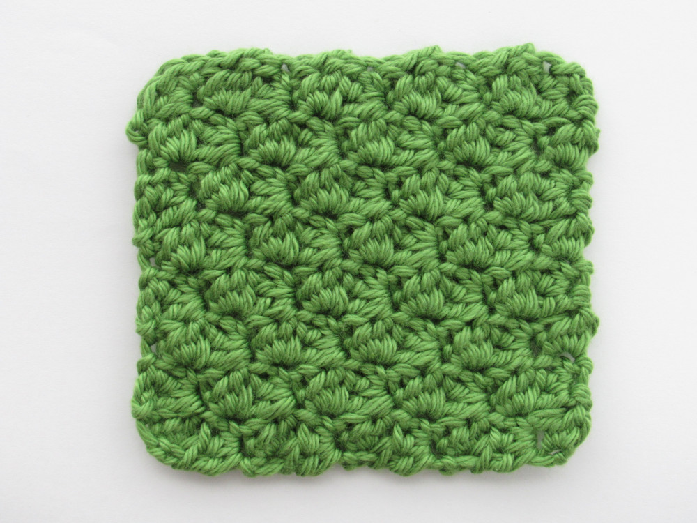 a green c2c sedge stitch crochet square. the sedge stitch is a pattern repeat of [sc, hdc, dc] in the scs of the previous row.