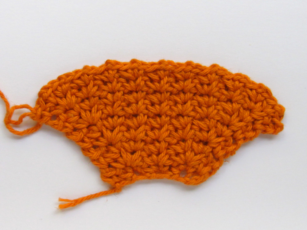 An orange spider crochet piece that gets wider with each row.