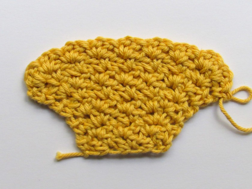 A yellow wattle stitch crochet piece that gets wider with each row.